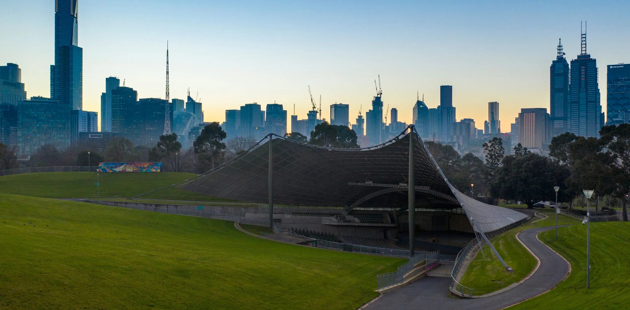 Drone view of the Sidney Myer Music Bowl at sunset with the Melbourne city skyline behind